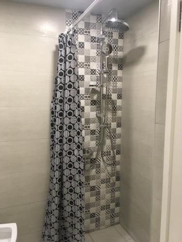 a shower with a black and white patterned shower curtain at Cozy Home in Old Tbilisi. in Tbilisi City