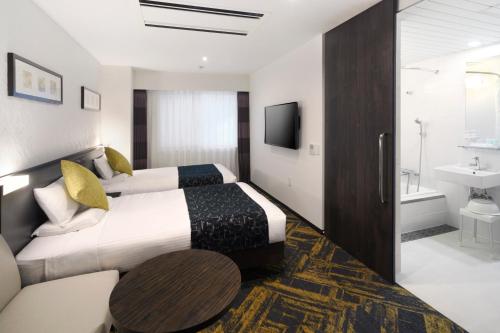 a hotel room with two beds and a bathroom at HOTEL MYSTAYS Hamamatsucho in Tokyo