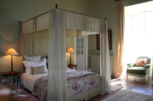 a bedroom with a canopy bed and a chair at Château de Camon in Camon
