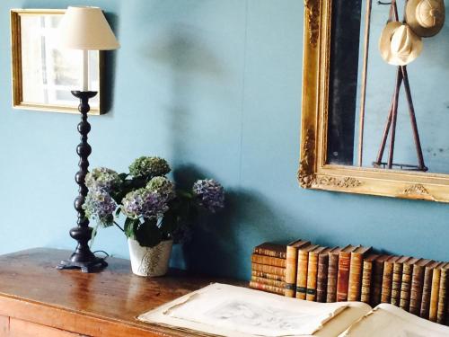 a table with a lamp a vase of flowers and books at Château de Camon in Camon