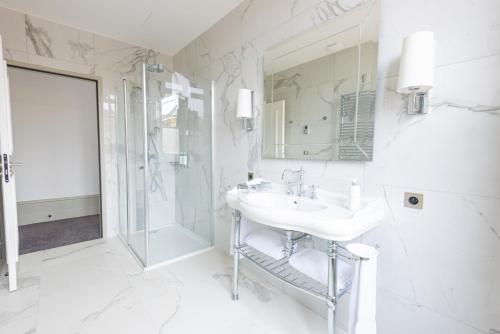 a white bathroom with a sink and a shower at Hôtel Mille Pas in Voiron