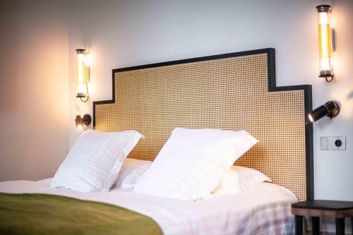 a bedroom with a large bed with white pillows at Hôtel Mille Pas in Voiron