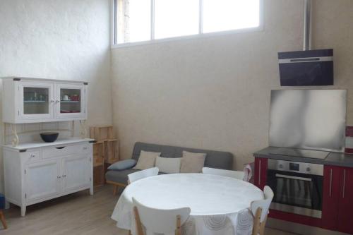 Il comprend un salon avec une table blanche et une cuisine. dans l'établissement Gîte rural 3 étoiles, 4 pers Puy du fou vendée ,montaigu clisson, côte vendéenne, à La Boissière-de-Montaigu