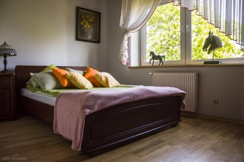 sypialnia z łóżkiem z poduszkami i oknem w obiekcie Leśne Zacisze w Iławie
