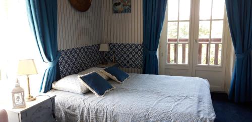 a bedroom with a bed with blue curtains and a window at LE CHALET SUISSE - Chambre bleue in Le Vicel