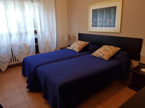 ポルト・サン・ジョルジョにあるAppartamento "Villa BMC"のベッドルーム1室(青いシーツとカーテン付きのベッド2台付)