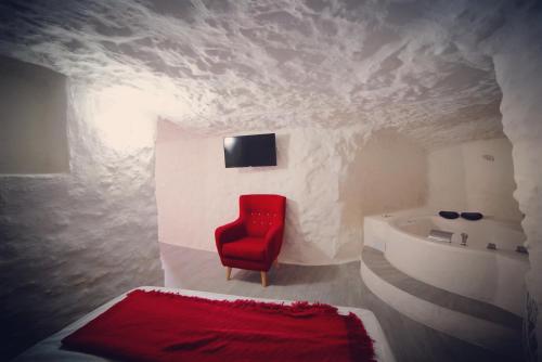 a room with a red chair and a bed at Casa Rural Las Colmenas in Alcalá del Júcar