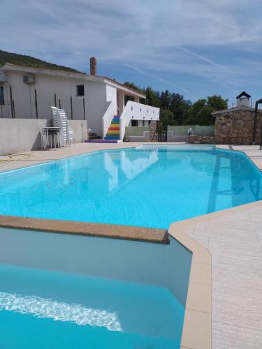 een groot blauw zwembad in een tuin bij B&B Daillu in Olbia