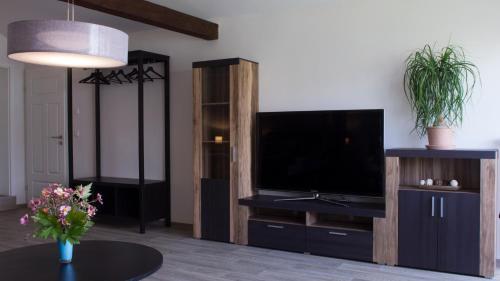 een woonkamer met een flatscreen-tv en een tafel bij Ringelnatz & Lichtwer- Ferienwohnung Wurzen in Wurzen