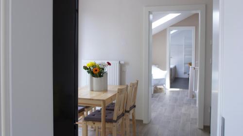 a dining room table with a vase of flowers on it at Ringelnatz & Lichtwer- Ferienwohnung Wurzen in Wurzen