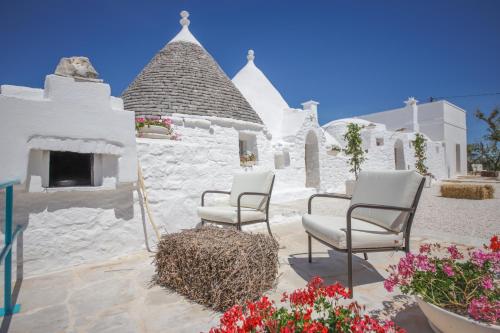a patio with chairs and flowers in front of a building at Petranima Wellness in Trulli in Ostuni