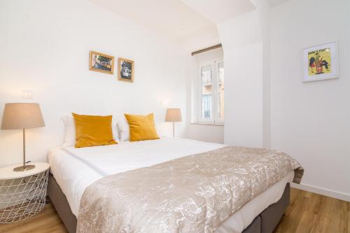 リスボンにあるWHome | Graça Premium Apartment #23のベッドルーム(オレンジ色の枕が付いた大きな白いベッド付)