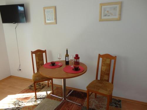 a table with a bottle of wine and two chairs at Pensjonat Aida in Kołobrzeg