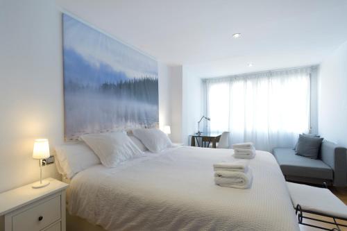 een slaapkamer met een wit bed en handdoeken bij Andrews house 60 m en el centro de Zaragoza in Zaragoza