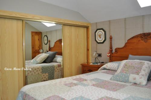 sypialnia z 2 łóżkami i dużym lustrem w obiekcie Casa Muro Ordesa w mieście Frajén