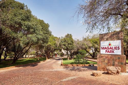 una señal para un parque de masias con árboles en el fondo en First Group Magalies Park, en Hartbeespoort