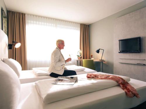 a man sitting on two beds in a hotel room at Mercure Hotel Plaza Essen in Essen