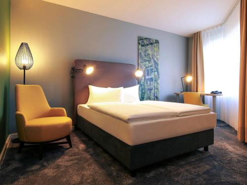 a hotel room with a bed and a chair at Mercure Hotel Plaza Essen in Essen