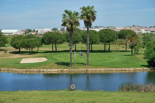 un campo de golf con palmeras y un estanque en La Quinta II by Ĥ, en Isla Canela