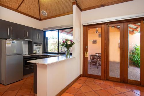 a kitchen with black cabinets and a counter with a vase of flowers at Bali Hai Resort & Spa in Broome