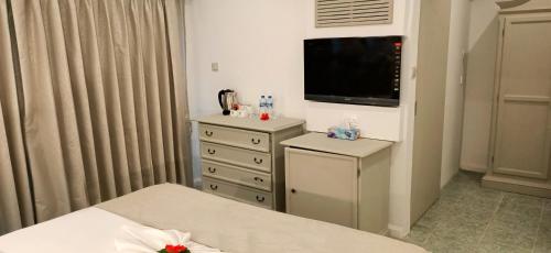 a bedroom with a bed and a dresser with a television at Le Relax Beach Resort in Grand'Anse Praslin