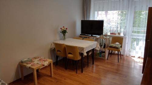 jadalnia ze stołem, krzesłami i telewizorem w obiekcie Apartament Jana z Kolna w Ustce