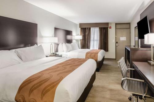 a hotel room with two beds and a desk at Quality Inn in Bristol