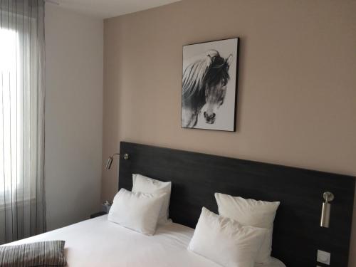a bedroom with a bed and a picture of a horse at Hôtel Saint Louis in Aigues-Mortes