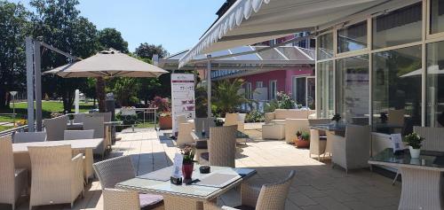 a patio with tables and chairs and an umbrella at Eden Hotel in Bad Krozingen