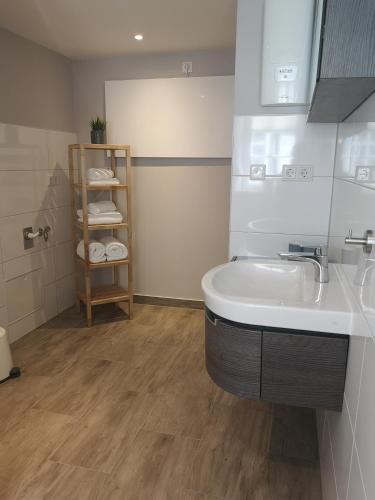 a bathroom with a sink and a shelf with towels at Ferienwohnung Telemann Stadtmitte in Eisenach