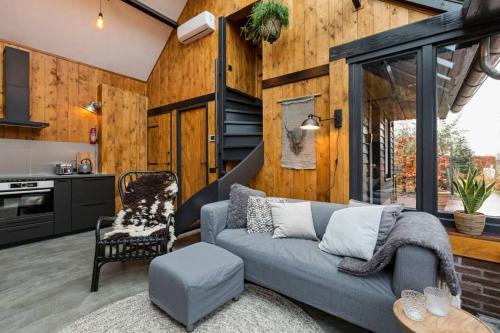 a living room with a couch and a kitchen at Uniek houten huis nabij bos en plassen in Hollandsche Rading