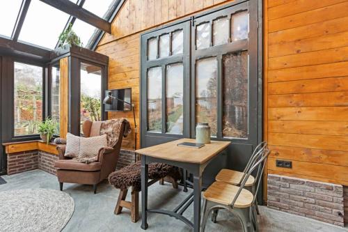 a room with a table and chairs and windows at Uniek houten huis nabij bos en plassen in Hollandsche Rading