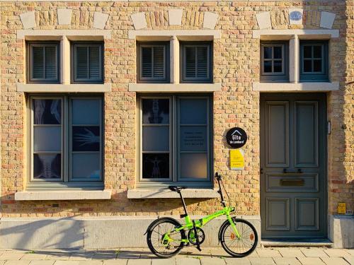 een groene fiets geparkeerd voor een bakstenen gebouw bij Gîte de Lombard in Ieper