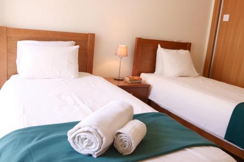 ein Hotelzimmer mit 2 Betten und Handtüchern darauf in der Unterkunft Ocean Terrace - Private Patio with BBQ & Sea view in Nazaré