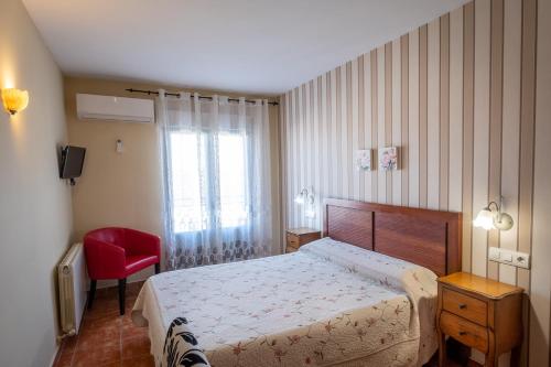 a bedroom with a bed and a red chair at Hotel La Jara-Arribes in Aldeadávila de la Ribera