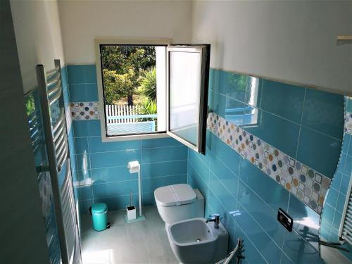 uma casa de banho azul com um WC e uma janela em Mimama em Telese Terme