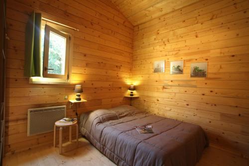 een slaapkamer met een bed in een houten hut bij "Les Collines d'Eyvigues" in Salignac Eyvigues
