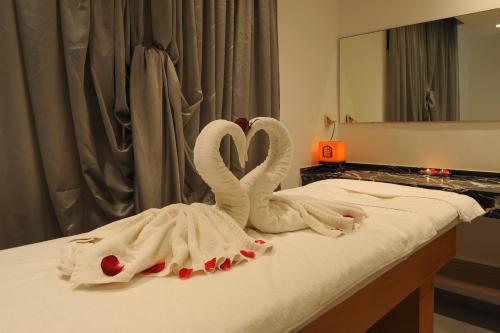 two towel swans sitting on a bed in front of a mirror at Radisson Blu Resort Taghazout Bay Surf Village in Taghazout