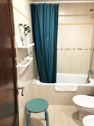 a bathroom with a blue shower curtain and a stool at Cotillo Ocean View in Cotillo