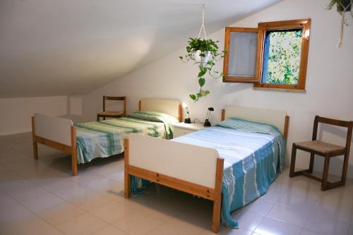 a bedroom with two beds and a table and a window at ELBA Casa Mare Natura in Magazzini