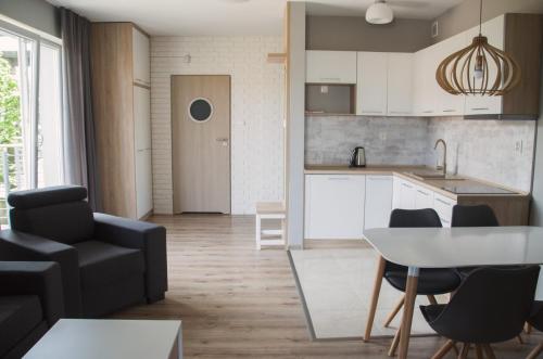 a kitchen and living room with a table and chairs at Apartament Przystań in Darłowo