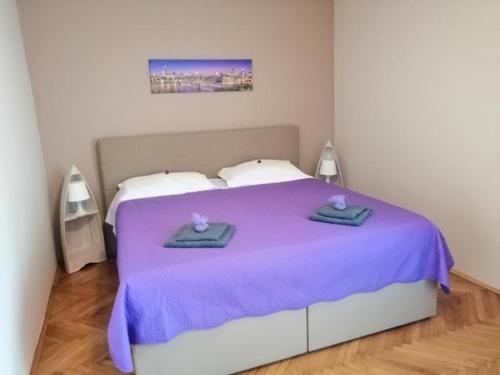 a bedroom with a purple bed with two towels on it at Apartman Sanja in Pula