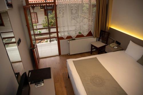 a bedroom with a bed and a chair and a window at Sinop Antik Otel in Sinop