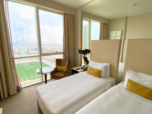 a hotel room with two beds and a large window at Centro Al Manhal by Rotana in Abu Dhabi