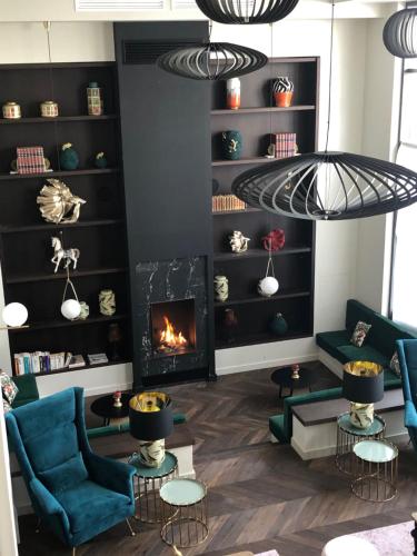 a living room with a fireplace and blue chairs at Hôtel La Villa Port d'Antibes & Spa in Antibes