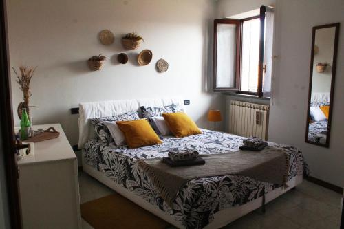 1 dormitorio con cama con almohadas amarillas y espejo en Casa all'era, en Cernobbio