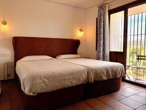 a bedroom with a bed and a large window at Hotel Don Miguel in Ronda