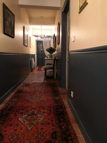 a hallway with a door and a rug on the floor at Les Chambres de L'Horloge in Lectoure