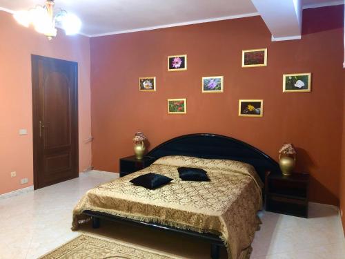 a bedroom with a bed and pictures on the wall at Villa Zagara in Gioiosa Ionica