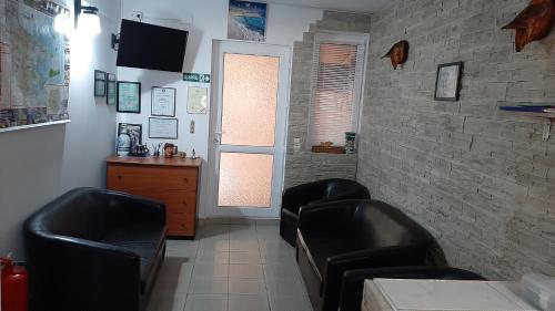 una sala de espera con sillas de cuero negro y una pared de ladrillo en Casa Diana, en Sulina
